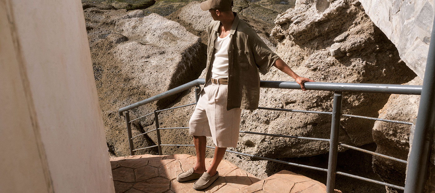 birkenstock визия мъжки модели от сезон пролет-лято 2025 - банер 2 с мъж подпрян на парапет до морски скали